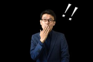 黒バックに手を口元にあてて驚く男性