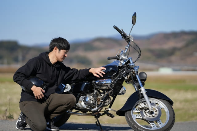 跪いてバイクに手を添える男性　　ブログ記事「I【RS4 125】　リアスプロケ歯数変更（やめて、その整備方法は危険！やってはいけないこと３選」のアイキャッチ